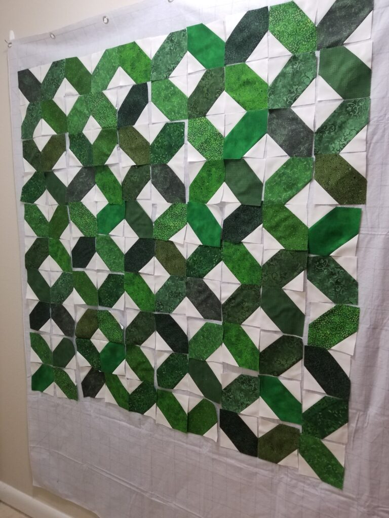 Green and white Xs and Os quilt blocks on a design wall.