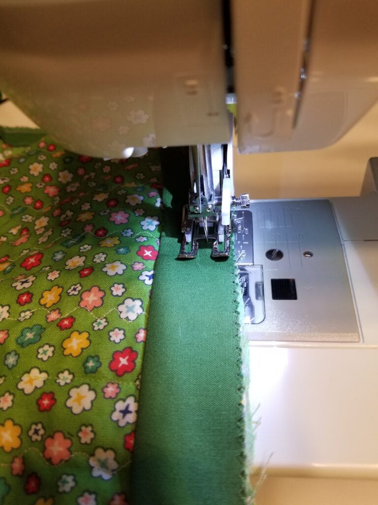 Machine sewing the binding to the back.