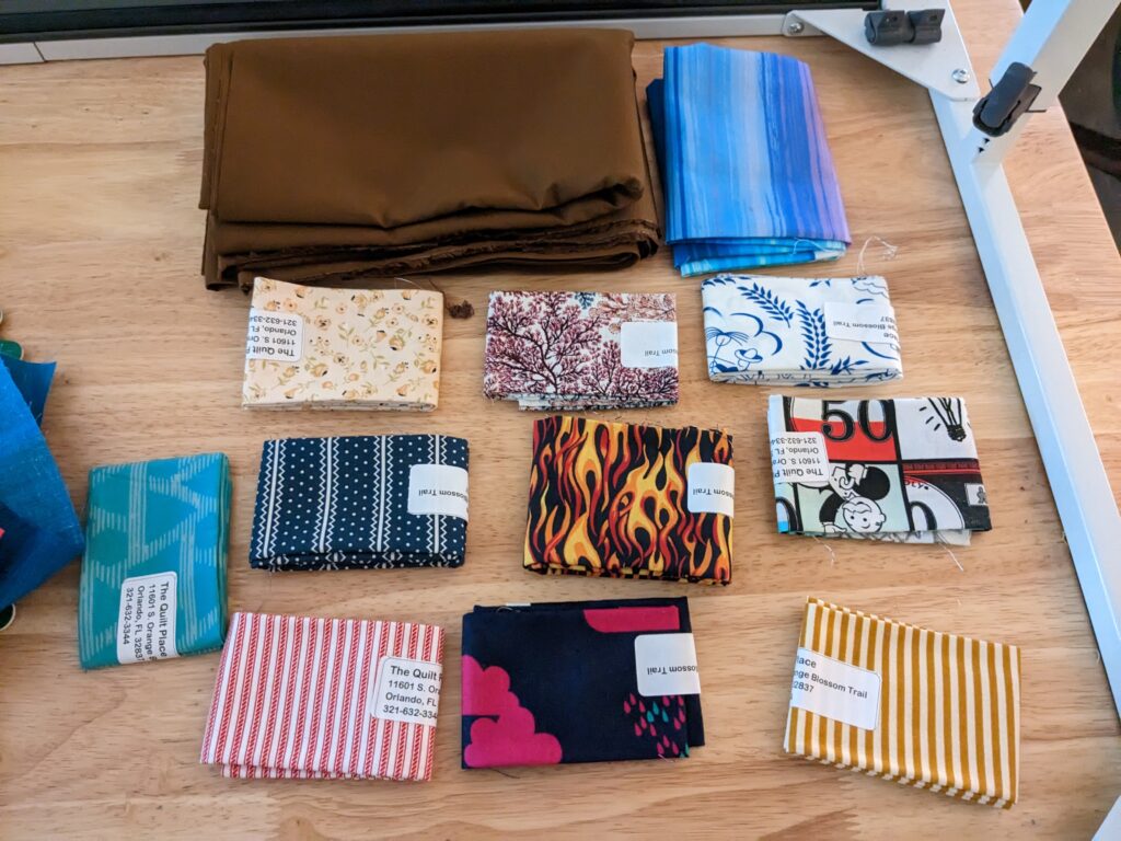 Fat eighths of fabric for the bookcase quilt, along with the brown fabric for the bookcase.