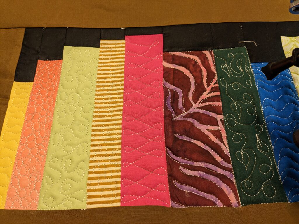 Close up of a few books showing a meandering leaf, ribbon candy, meandering loops and pebbles.