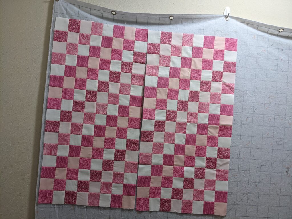 Part of the Around the World quilt in pinks laid out on my design wall.