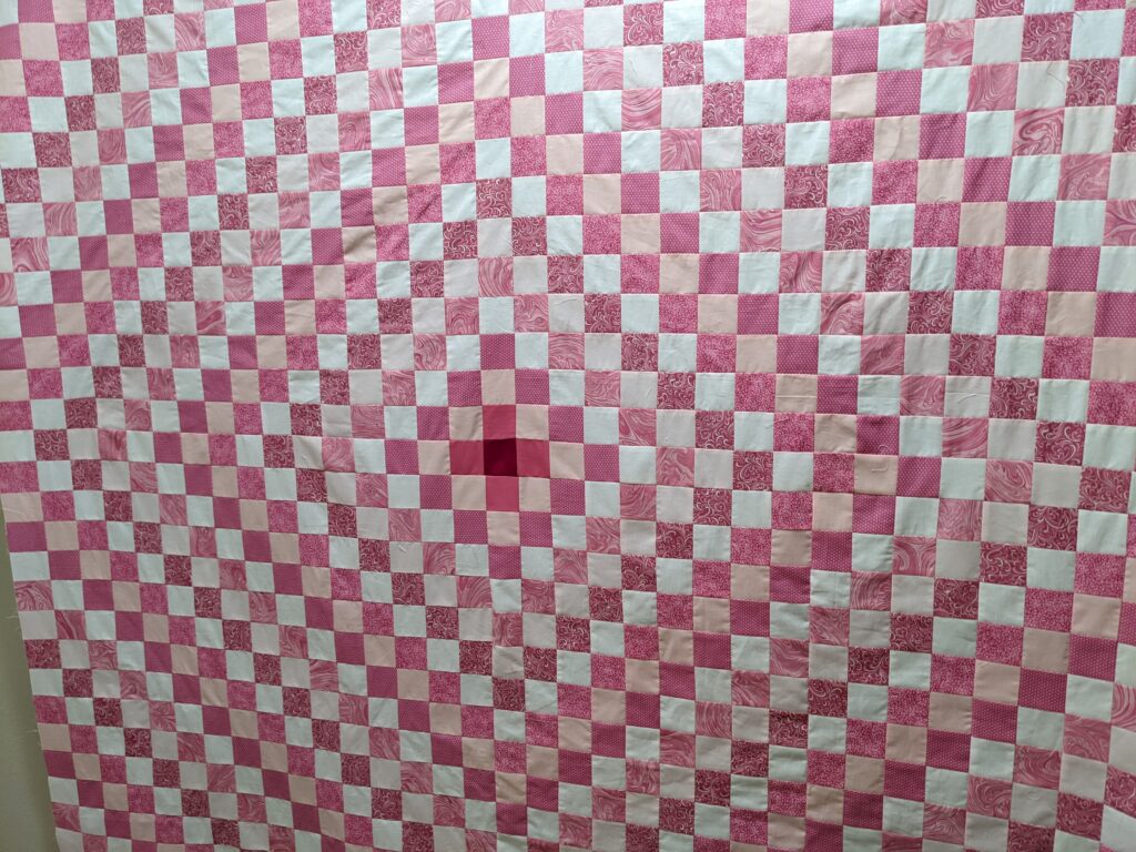 Fully sewn Around the World quilt top hanging from my design wall.