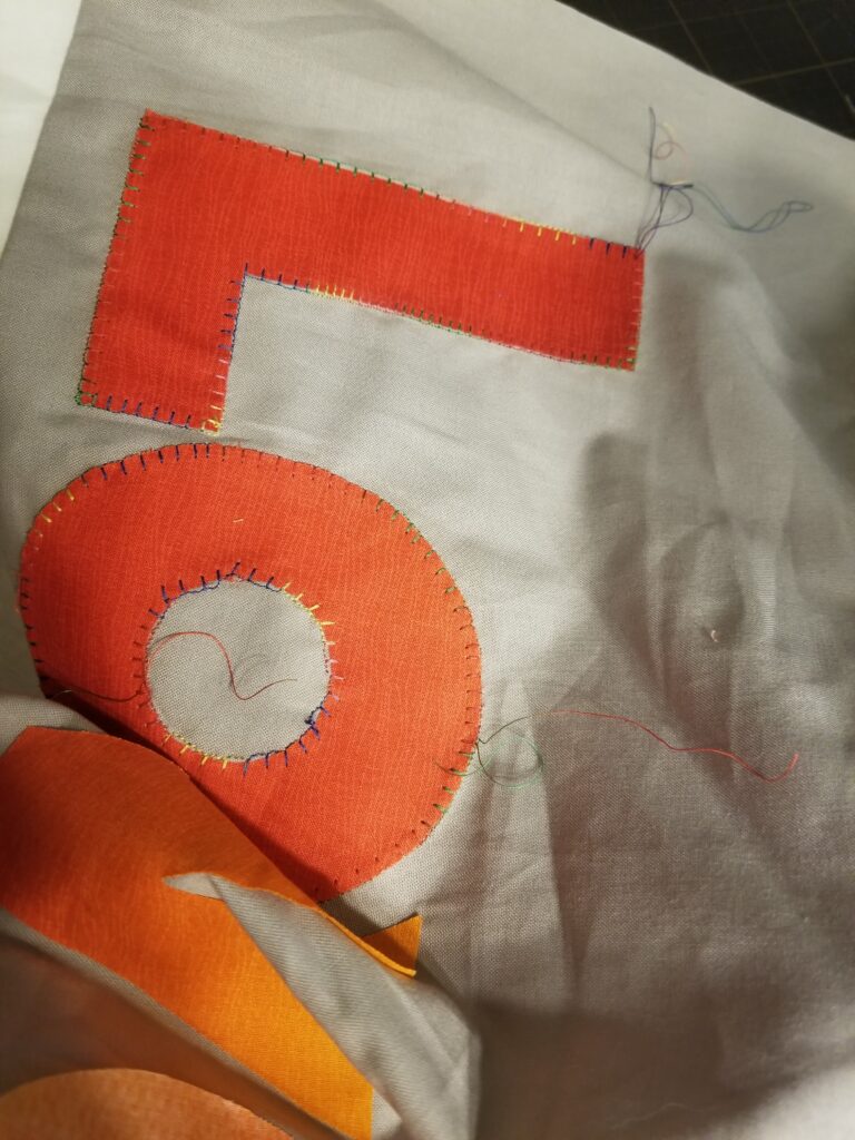 Letters L and O appliqued to a quilt top for the Love is Love second quilt attempt.