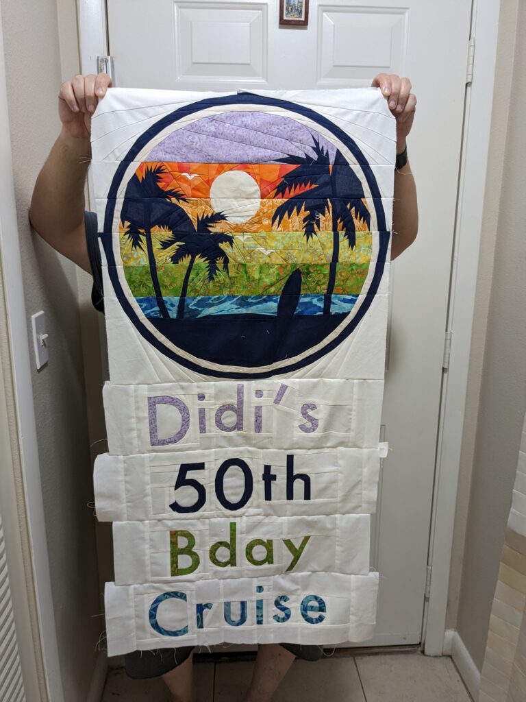 My husband holding up the fully sewn wall hanging, prior to quilting.