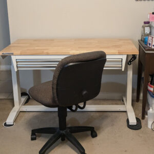 A Husky brand table against the wall in my living room with my office style chair in front of it.